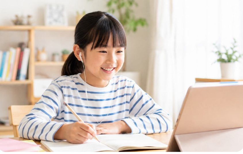 ノートパソコンとノートを広げて学ぶ子ども